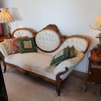 Antique Victorian carved wood and white upholstered sofa. Antique kidney shaped wood side tables. Pair of antique statue lamps. 