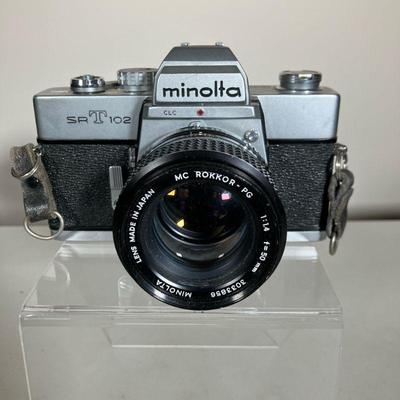 MINOLTA SR-T 102 CAMERA LOT | A Minolta SR-T 102 35mm Camera with original box, all manuals, lens caps and two Minolta lenses. A 50mm 1.4...