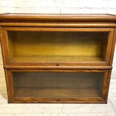 WIII217 Macey Barrster	2 piece bookcase made out of oak. Both glass doors slide up and in. Does have some stains on top of the bookcase...