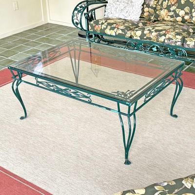 WROUGHT IRON & GLASS OUTDOOR COFFEE TABLE | Glass-topped outdoor coffee cable with wrought iron floral designs over cabriole legs raised...