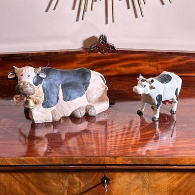 (2PC) DECORATIVE COWS, ONE CAST IRON | Including a painted cast, iron cow, form bank, and a composition painted cow. - l. 14 in (largest)

