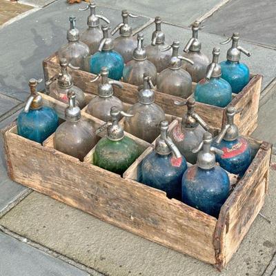 (20PC) ANTIQUE SELTZER BOTTLES | Including 12 clear glass bottles, seven blue glass bottles, and one green glass bottle in two wooden...