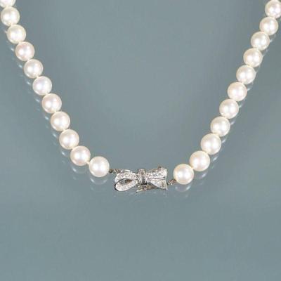 PEARL NECKLACE WITH DIAMOND CLASP | Designed as a strand of white 9 mm pearls terminating in a platinum and diamond bow-form clasp; 16...