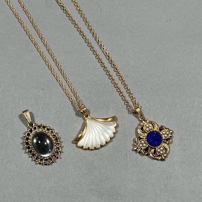(3PC) PENDANT NECKLACES | Two gold-tone costume pendant necklaces, one by Avon with a lapis-style pendant and one with a fan-form...