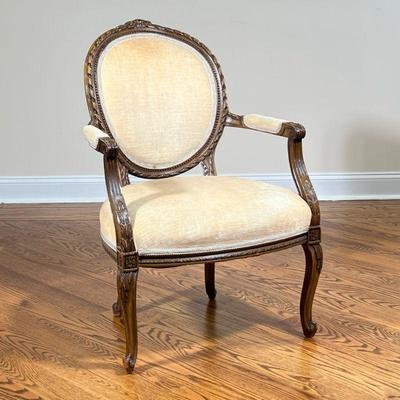 LOUIS XVI STYLE SLIPPER ARM CHAIR | Champagne upholstered Louis XVI slipper chair with fluted arms and floral carved accents over...