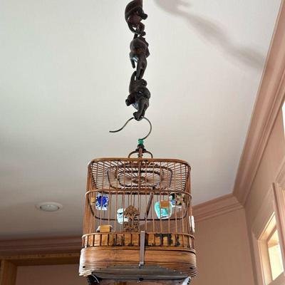 CHINESE BIRDCAGE | Suspended by three carved wood monkeys, the interior with miniature ceramics, and a single crossbar. - l. 8 x w. 8 x...