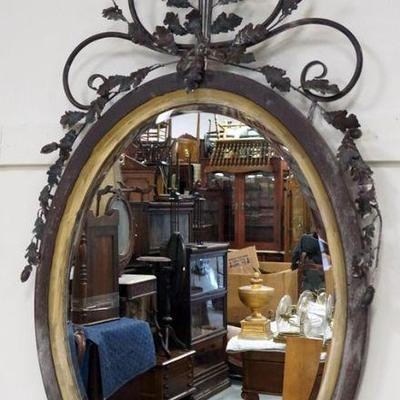 1184	LARGE OVAL BEVEL EDGED HANGING MIRROR WITH METAL SCROLLED VINE AND LEAVES AT TOP, APPROXIMATELY 30 IN X 53 IN
