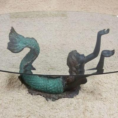 1081	BRONZE MERMAID FORM COCKTAIL TABLE WITH OVAL GLASS TOP, SIGNED ON BASE, APPROXIMATELY 49 IN X 28 IN X 19 IN H
