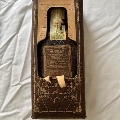 1917 Pre-Prohibition prescription whiskey bottle, unopened, in original paper and tin packaging, minor patina on top, no evaporation of...