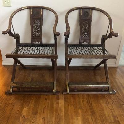 Chinese Horseshoe Back Folding Chairs with Leather seat straps, brass accents and carved wood.