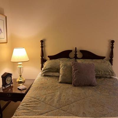 Queen sized bed includes wood headboard, metal, bedframe, boxspring, and mattress.