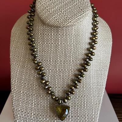 Strand of green freshwater pearls with a triangular citrine pendant set in silver