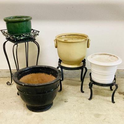 NIAD110 Outdoor Pots And Stands	Two matching stands are heavy iron. Taller one has a decorative leaf trim. The white pot looks to be...