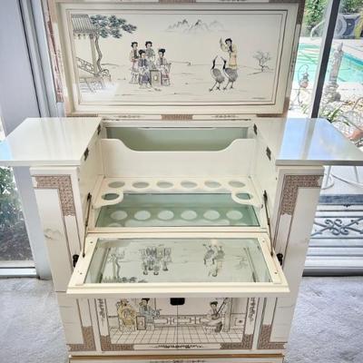 Ivory chinoiserie pulldown wet bar. Both sides open to hold wine glasses, bottom opens to hold bottles, and top opens for bar. 