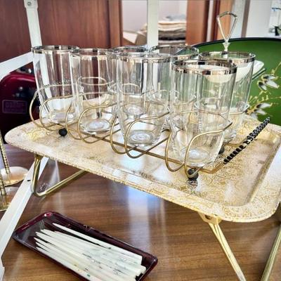 Two of two vintage metal glass/barware caddies and 1960s gold collapsible serving tray. Also pictured are set of tiny vintage square candles