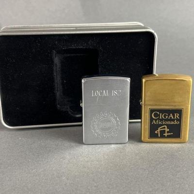 Lot 575 | Brass Cigar Aficionado & UAW Zippos