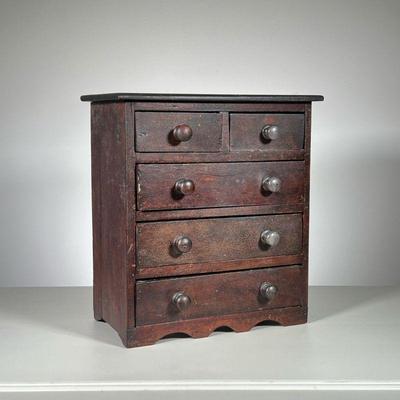 MINIATURE DOVETAILED CHEST | Chest in old dark finish, crackled and worn. Two drawers over four with wood knobs. - l. 15 x w. 8 x h. 16 in

