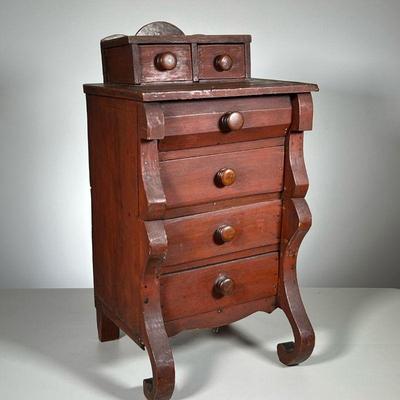 MINIATURE CHEST | Child’s two drawers over four in a red stain with scroll feet. - l. 13 x w. 10.5 x h. 12.5 in

