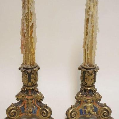 1090	PAIR OF ORNATE EMBOSSED COPPER SHEATHED POLYCHROME CANDLESTICKS WITH IMAGES OF LION HEADS AND CHERUBS, EACH APPROXIMATELY 8 IN H
