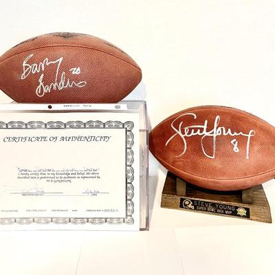 Two Signed Footballs by Players Barry Sanders and Steve Young