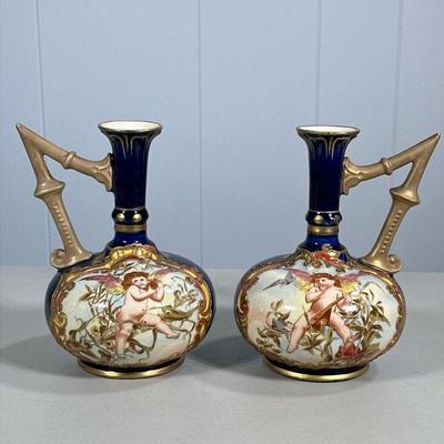 (2PC) PAIR FISHER J. BUDAPEST PITCHER | Pair of cobalt glazed Fisher J. Budapest vases with portrait of cupids and gilt accents. - h. 7.5...