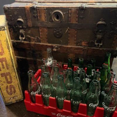 Very old trunk and vintage soda bottles.
