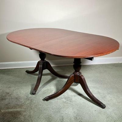 MAHOGANY DINING TABLE | Mahogany wood dining table with two extension leaves, of nicely figured wood, with carved double pedestal legs. -...