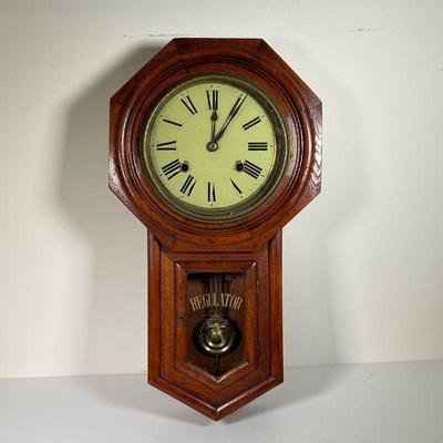 ANTIQUE DEA REGULATOR MECHANICAL WALL CLOCK | Mechanical wall clock in good condition with wind up key. - l. 12 x w. 4-1/4 x h. 22 in

