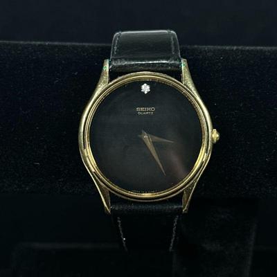 SEIKO QUARTZ WRISTWATCH | In the style of Movado having black dial and gold-toned top with stainless steel case and black leather band. -...