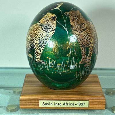 PAINTED OSTRICH EGG | Hollowed & painted ostrich egg decorated with various African animals on stand with label “Savin into...