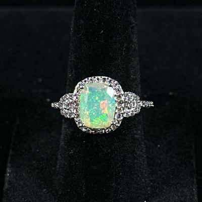 OPAL & STERLING RING | Designed as a sterling silver ring with large mounted opal bordered by melee diamond simulants, size 6, marked...