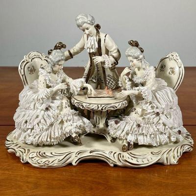 DRESDEN PORCELAIN CHESS FIGURINE | Depicting 2 women in porcelain lace dresses playing chess with male onlooker. - l. 12 x w. 6 x h. 8.5...