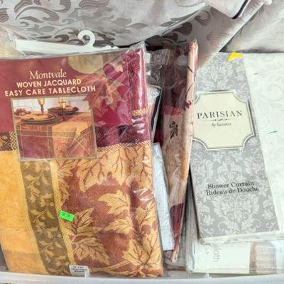 Many unopened packages of linens, tablecloths, sheets, bedding. shower curtains.