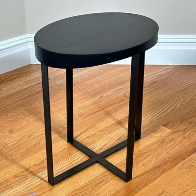 Modern Oval Side Table | Having a black wood top over metal legs. - l. 19 x w. 14.5 x h. 22 in

