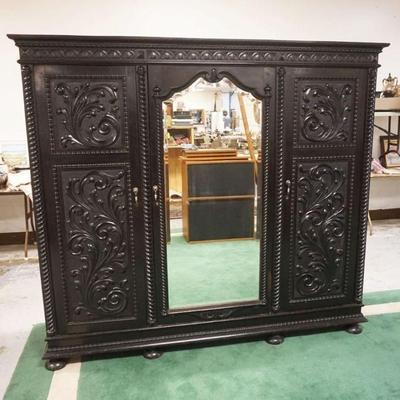 1217	ORNATE CARVED 3 DOOR CABINET WITH BEVELED GLASS CENTER MIRROR AND ADJUSTABLE SHELVES IN AN EBONIZED FINISH, APPROXIMATELY 84 IN X 26...