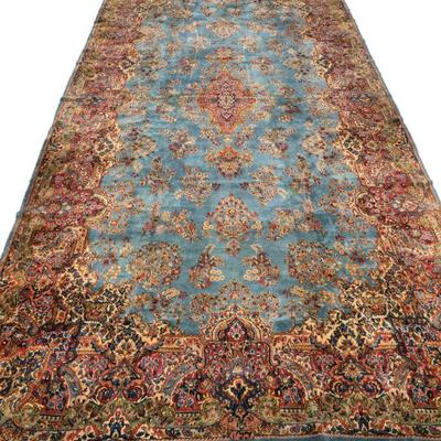 ANTIQUE SKY BLUE KIRMAN PERSIAN CARPET | Early 20th century, having a blue ground with beige, red, and green border, signed - l. 217 x w....