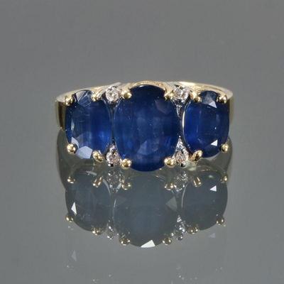 TRIPLE SAPPHIRE & 14K GOLD RING | Designed as a central oval mixed cut sapphire (9 x 6.7 x 3.7mm), flanked by two smaller oval mixed...