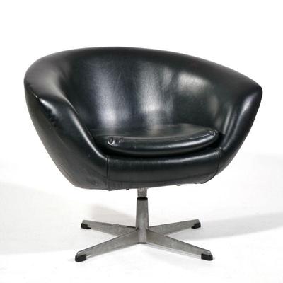 MID CENTURY LOUNGE ARMCHAIR | Black leatherette/ vinyl covering, single cushion on a swiveling cast aluminum quadruped base, surprisingly...