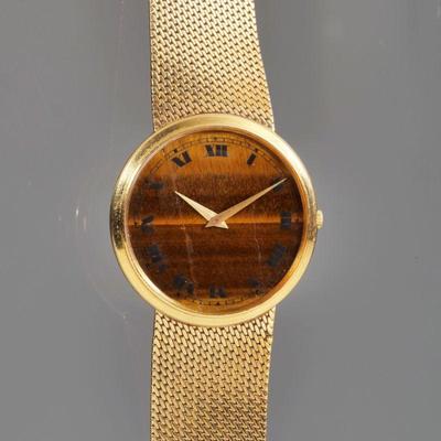 VINTAGE PIAGET 18K GOLD & TIGER'S EYE WRISTWATCH | Designed as a round tiger's eye quartz face with painted roman numerals, spade hands,...