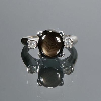 BLACK QUARTZ CABOCHON, DIAMOND & 14K GOLD RING | Designed as a central phenomenal black quartz (11 x 9.2 x 5 mm) flanked by two full...
