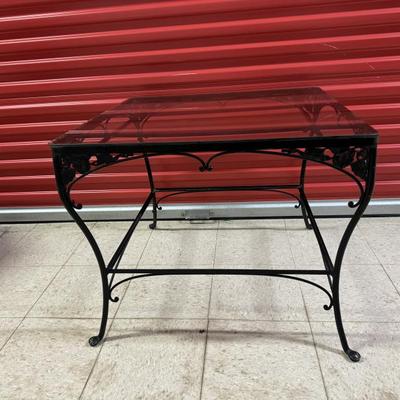 Vintage black wrought iron square metal table with glass top. Measures 28 1/2” square and 24” tall. Intricate floral and scroll metal...