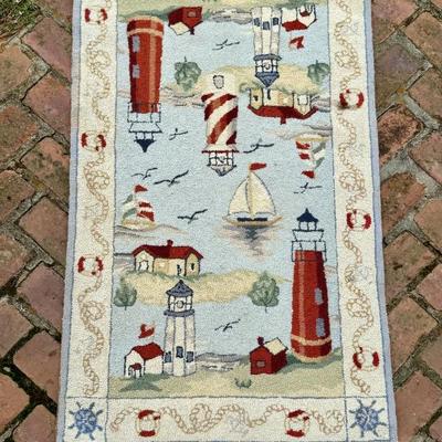 Hand hooked wool rug featuring lighthouse motif. Measures 49 inches long and 29 inches wide. 