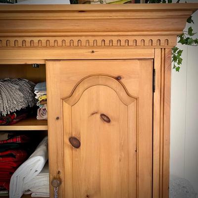 Pine armoire filled with linens (tablecloths, runners, napkins, and placemats) and fabric remnants