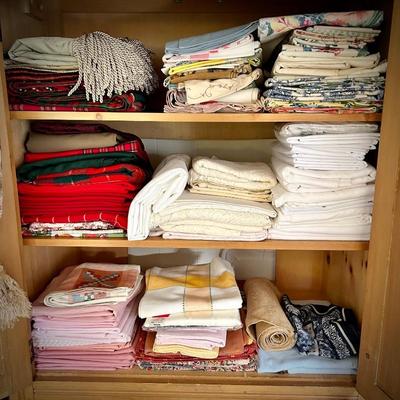 Pine armoire filled with linens (tablecloths, runners, napkins, and placemats) and fabric remnants