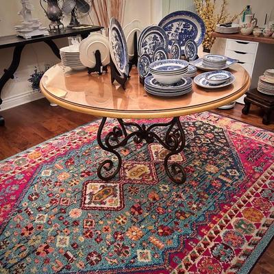 Area rug and circular wood table with glass top and black metal legs