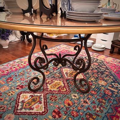 Area rug and circular wood table with glass top and black metal legs