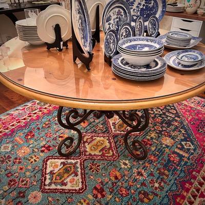 Area rug and circular wood table with glass top and black metal legs