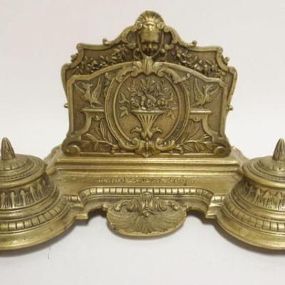 Sale Photo Thumbnail #96: 1096	ORNATE BRASS LETTER HOLDER W/DOUBLE INKWELLS & PEN HOLDER TRAY, EMBOSSED CHERUB HEAD AT CREST, GLASS INSERTS MISSING, APPROXIMATELY 12 IN X 8 IN X 7 IN HIGH
