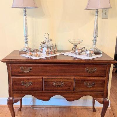 Cherry lowboy with collection of silver items and mercury glass lamps