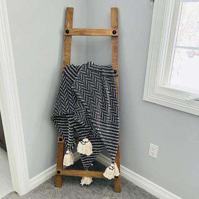 Beautiful boho patterned blanket with tassels draped over a wooden ladder.